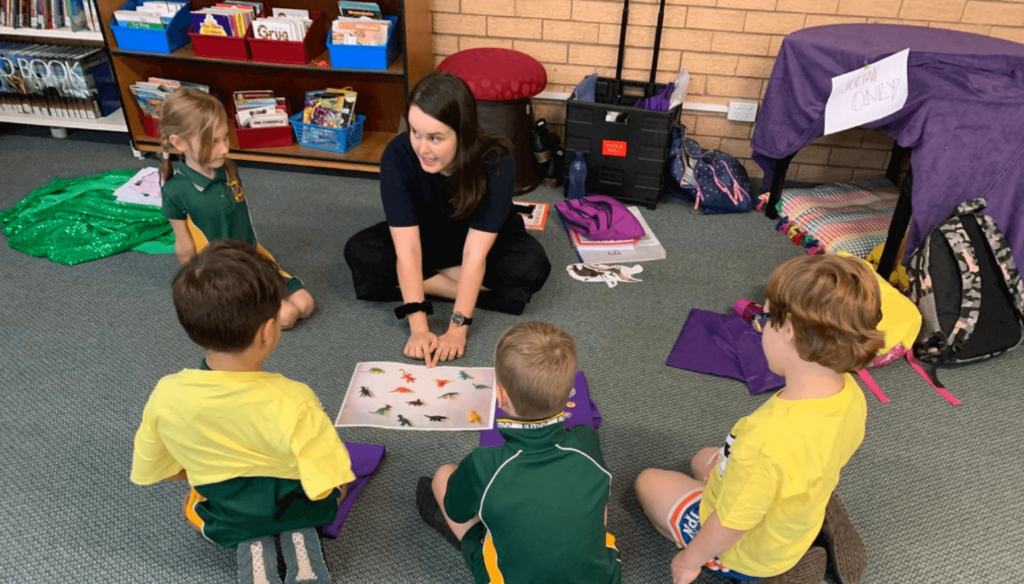 Teacher with young students sitting on the floor