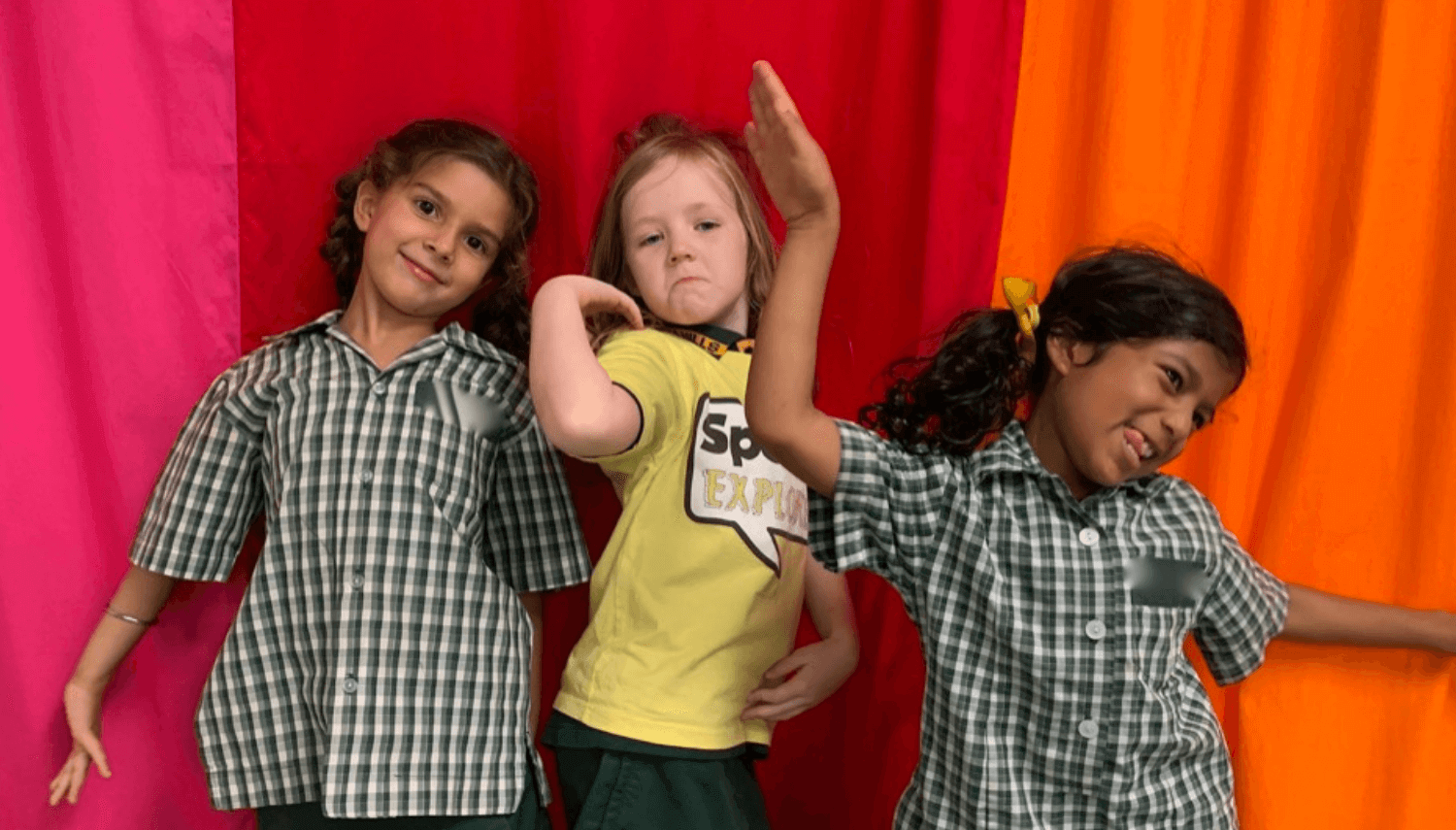 young drama students posing in front of a red curtain