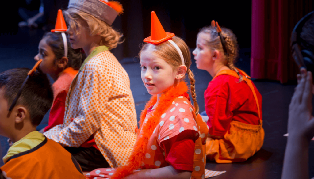 chidlren sitting side stage at drama performance